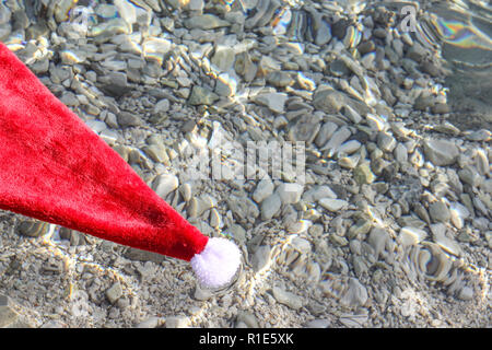 Santa Claus hat floating in tropical sea waves, christmas vacation on sea concept Stock Photo