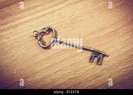 Retro styled decorative key placed on wooden texture Stock Photo