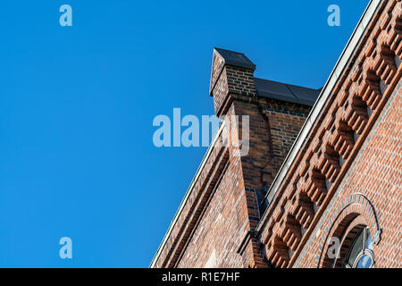 Old historical brick warehouse facade detail in Sandtorkai Hof, Speicherstadt, Hamburg, Germany against a sunny blue sky.