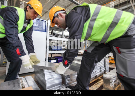 Workers taking aluminium billet at CNC machine shop Stock Photo