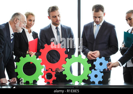Business people assembling cogwheels, teamwork concept Stock Photo