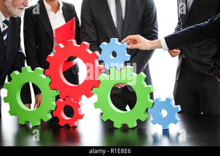 Business people assembling cogwheels, teamwork concept Stock Photo