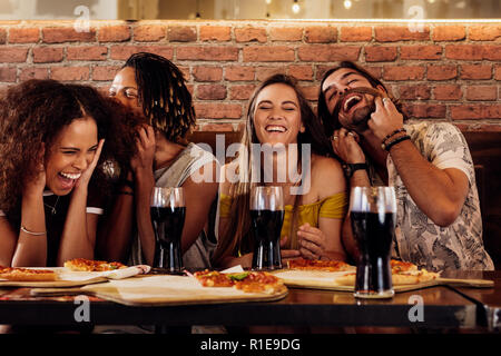 Group of happy multiracial friends having party at pizza restaurant. Cheerful young friends hanging out at restaurant. Stock Photo