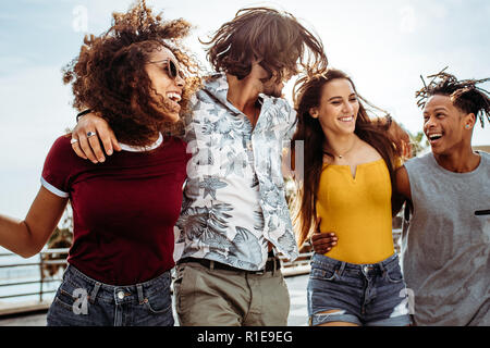 Four young people walking outdoors together. Group of multi-ethnic men and women having fun outdoors. Stock Photo