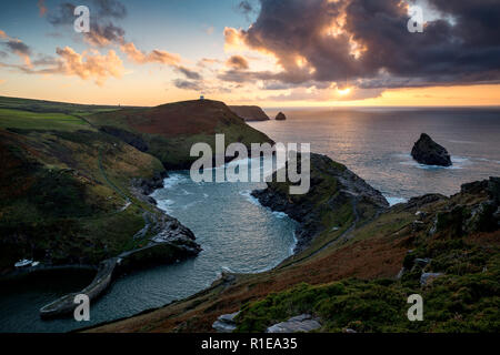 Boscastle harbour mouth entrance on the North coast of Cornwall at sunset in the Autumn with beautiful clouds in the sky and warm golden colours Stock Photo