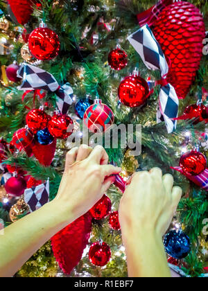 Woman hand decorates Christmas tree with different kind of decorations Stock Photo