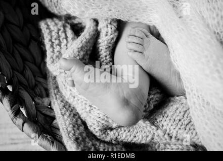 Gloomy black and white photo close up of a newborn baby feet toes under a white soft knitted blanket, baby loss concept. Stock Photo