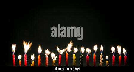Set of eighteen different color shape and pattern birthday candles burning flames in motion, long exposure in dark isolated on black. Happy Birthday c Stock Photo