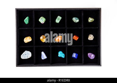 Flat lay view of variety of colorful semi precious stones crystals in organizer box sorted by color isolated on black. Stock Photo