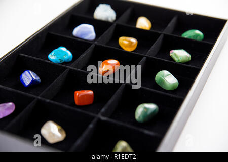 Variety of colorful semi precious stones crystals in organizer box sorted by color isolated on black. Stock Photo