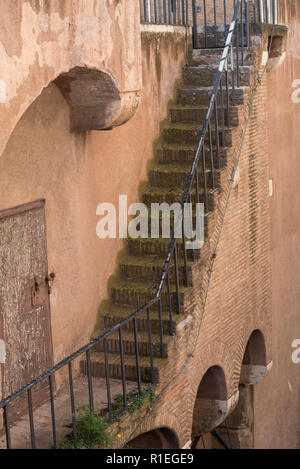 The wall of the building with a brick wall and a staircase with metal railings goes down. Old building. Stock Photo