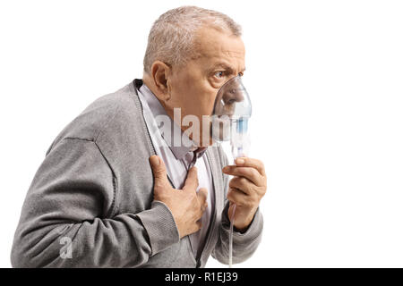 Elderly man with asthma using an inhaler and holding his chest isolated on white background Stock Photo