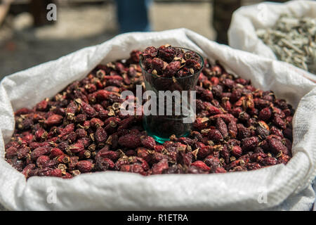 Dried rose hips in a sack at a market for sale. Dog roses Close up shot. Stock Photo