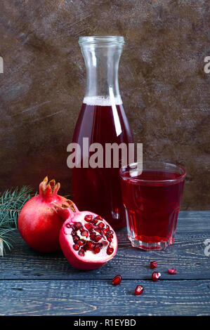 A glass of fresh pomegranate juice with ripe pomegranate fruits on wooden table. Vitamins and minerals. Healthy drink concept. Vertical view Stock Photo