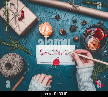 Christmas composition, a girl signs an envelope, toys and New Year's attributes are laid out, a place for text Stock Photo