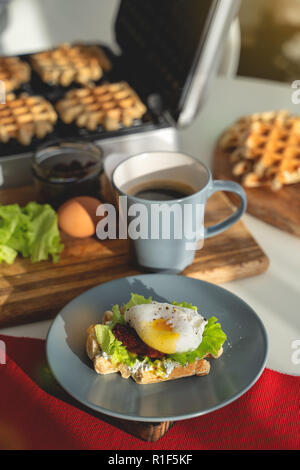 Eggs Benedict with bread and tomato on a plate with becon morning sandwich. Stock Photo