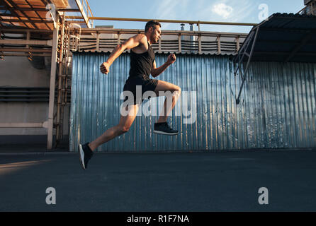 Handsome young man running in ndustrial building background.  runner, jogger, fitness activity Stock Photo
