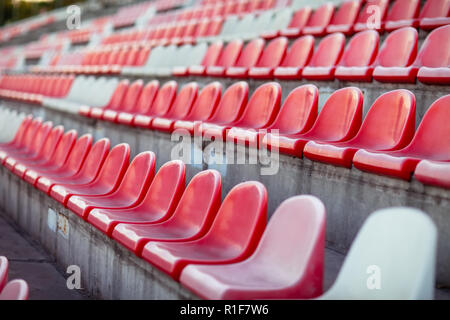 Rows of empty seats in a sports stadium. Red and white plastic chairs waiting for fans Stock Photo