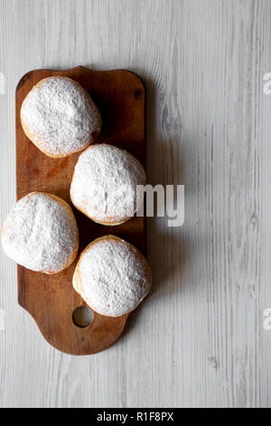 Homemade donuts with jelly and powdered sugar on rustic wooden board over white wooden background, top view. Copy space. Stock Photo