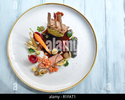 Pork loin with beetroot dumplings on black sauce with seasonal cooced vegetables Stock Photo