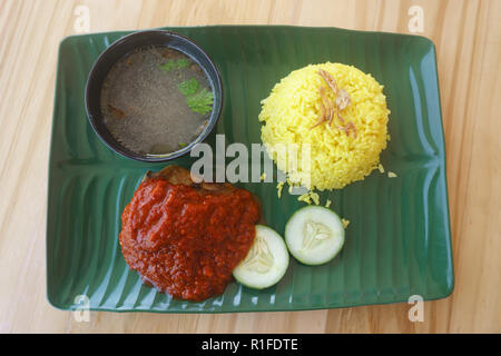 'Nasi Kuning' meal on table setup. Nasi Kuning is Indonesian cuisine. fried chicken dish consisting of fried chicken , served with sambal, slices of c Stock Photo