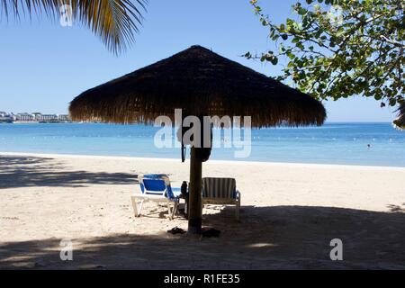 Beach shade provided by a thatched straw umbrella Stock Photo