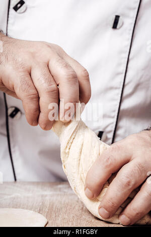 male chef kneads the dough, hands closeup Stock Photo