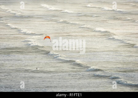 Woolacombe Beach, North Devon, UK 12th November 2018. A lone kite surfer battles the waves and gusty winds at Saunton on the North Devon Coast on a day of mixed sun and showers. Credit: Julian Eales/Alamy Live News Stock Photo