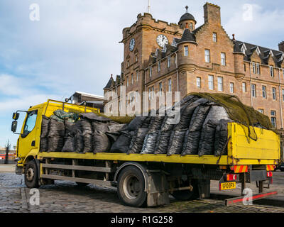 Yellow flatbed  lorry delivering coal sacks with Malmaison Hotel, Tower Place, Leith, Edinburgh, Scotland, UK Stock Photo