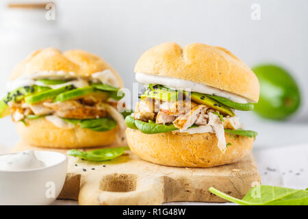 Grilled chicken and avocado burger on wooden board. Healthy food concept.