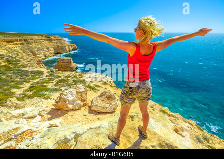 Freedom young woman at Island Rock, a natural limestone in Australian Coral Coast, Kalbarri National Park. Scenic panorama of turquoise Indian Ocean. Sunny with blue sky. Western Australia Outback. Stock Photo