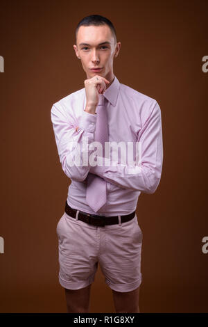Young handsome androgynous businessman against brown background Stock Photo