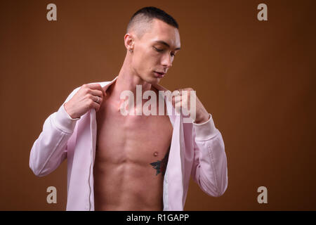 Young handsome androgynous man against brown background Stock Photo