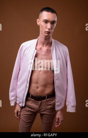 Young handsome androgynous man against brown background Stock Photo