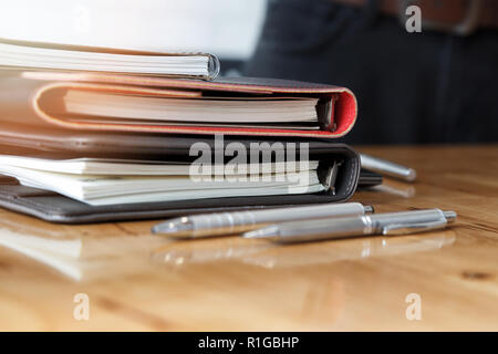 Stack of notebooks and pens on office desk Stock Photo