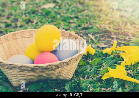 Bright colorful Easter eggs in a basket on green glass. Holidays concept. Stock Photo