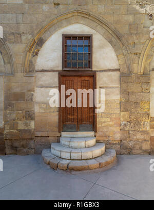 Old wooden door and window framed by arched bricks stone wall at the courtyard of al Razzaz historic house, Darb al Ahmar district, Old Cairo, Egypt Stock Photo