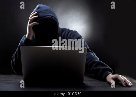 tired hacker without face in a hood on a dark background Stock Photo