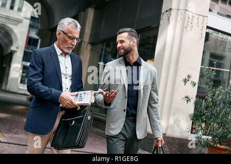 Two businessmen discussing about the new project while walking outdoors. Stock Photo