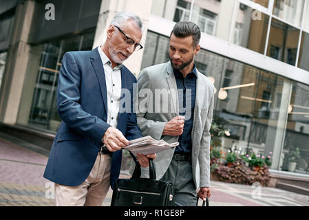 Two businessmen discussing about the new project while walking outdoors. Stock Photo