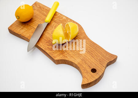 Sliced fresh lemon over chopping board.environmentally friendly, ecological products.prevention of colds.Sliced and whole lemons on cutting board with a knife .Copy space Stock Photo