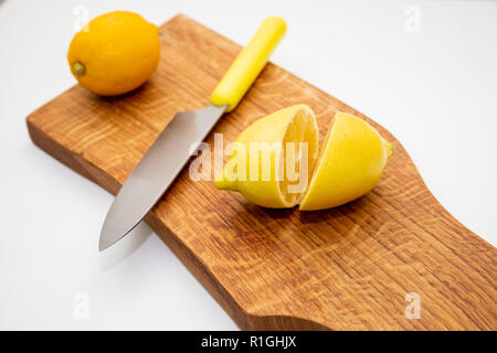 Sliced fresh lemon over chopping board.environmentally friendly, ecological products.prevention of colds.Sliced and whole lemons on cutting board with a knife .Copy space Stock Photo