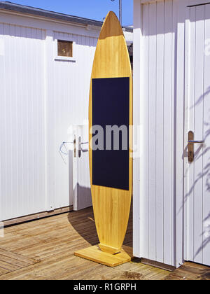 A blackboard shaped Surfboard on a beach white booths. Stock Photo