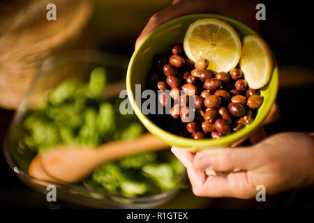 Hands holding a bowl of olives and two lemon slices. Stock Photo