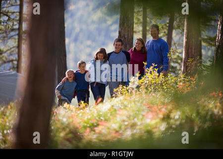 Happy family standing with their arms around each other through a forest. Stock Photo