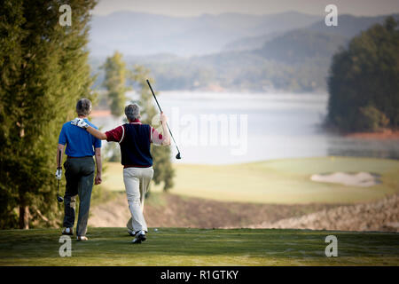 Two mature men enjoying a game together on a golf course. Stock Photo