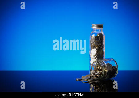 Saving concept with mason jar,coins and piggy bank on a blue background. Stock Photo