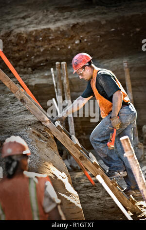 Mid-adult man wearing a hard hat demolishing a building. Stock Photo