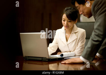 Young adult business woman using a laptop in a boardroom. Stock Photo