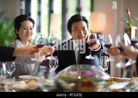 Business colleagues making a toast with glasses of red wine while seated around a table. Stock Photo